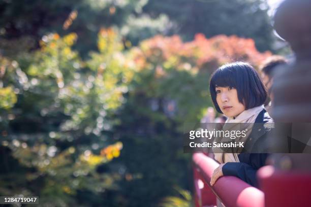 young woman looking at view of autumn leaves from bridge - kobe japan stock pictures, royalty-free photos & images