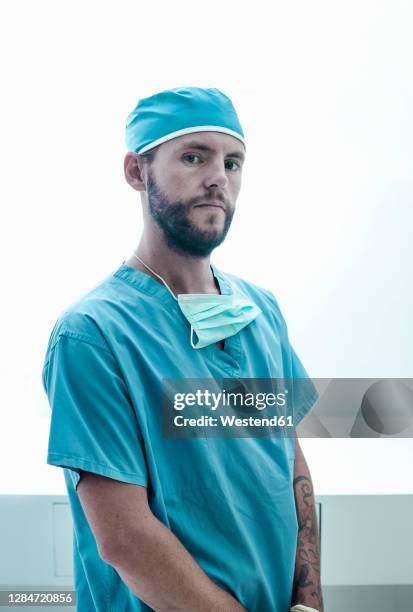 confident male surgeon standing at illuminated hospital - chirurgenkappe stock-fotos und bilder