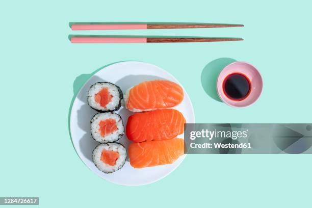 studio shot of chopsticks, bowl of soy sauce and plate of maki sushi and nigiri - maki sushi stockfoto's en -beelden