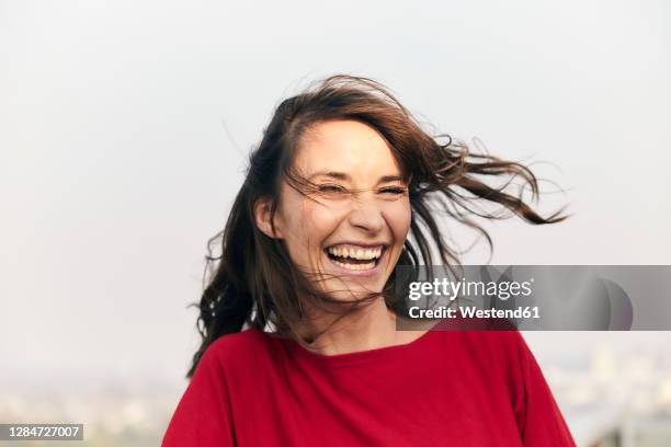 cheerful woman standing against clear sky - face wind photos et images de collection