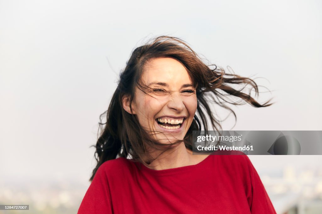 Cheerful woman standing against clear sky