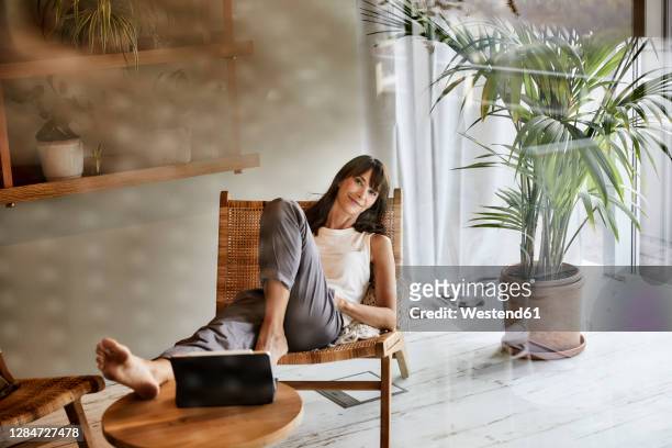 woman resting while sitting on chair at home - low key stock-fotos und bilder