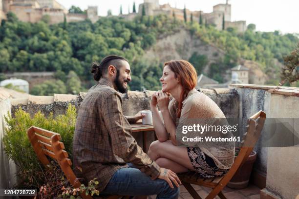 smiling couple sitting by table on roof top at home - granada spain stock pictures, royalty-free photos & images