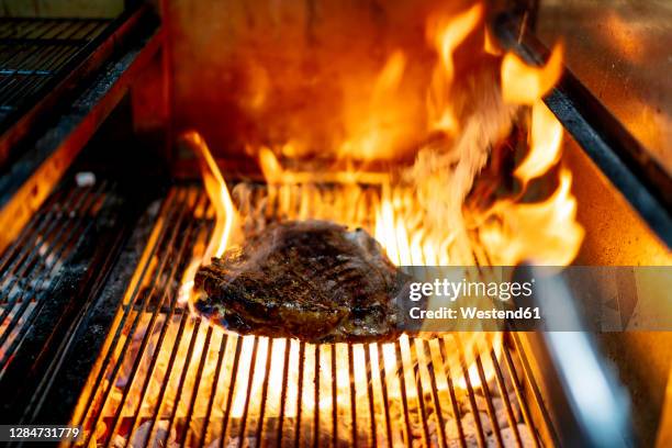 meat being roasted on barbecue grill at restaurant - grill fire meat stock pictures, royalty-free photos & images