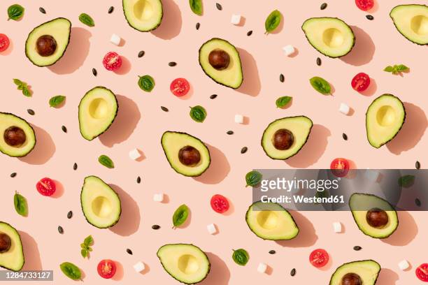 pattern of halved avocados and cherry tomatoes, pumpkin seeds, basil and pieces of cheese - repetition stock-grafiken, -clipart, -cartoons und -symbole