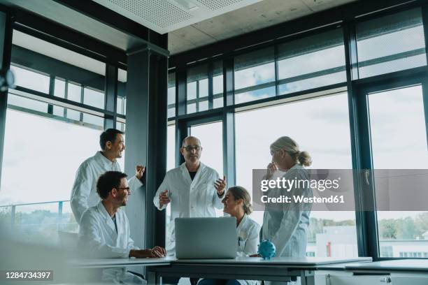 doctors and scientist having discussion while standing at office - scientist standing next to table stock-fotos und bilder