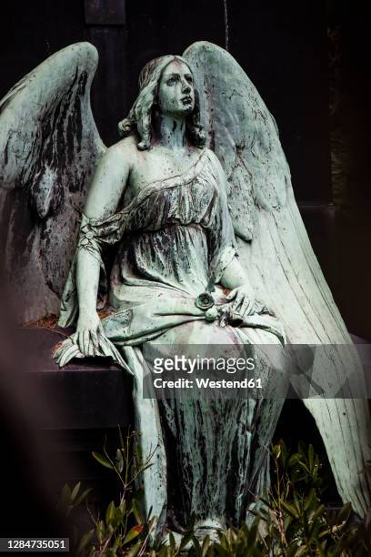 weathered statue of sitting angel - angel statue stock-fotos und bilder