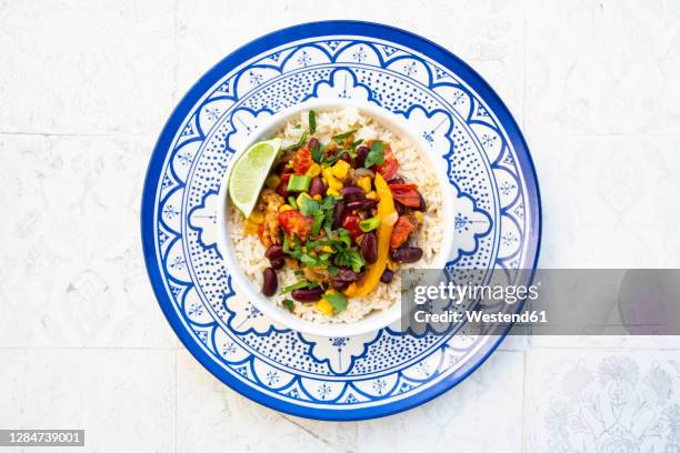 bowl of mexican rice with tomatoes, bell pepper, tofu, kidney beans, corn, scallion and lime - limes plate no people stock pictures, royalty-free photos & images