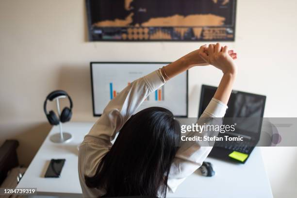 kvinna som sträcker sig medan du arbetar från ett hemmakontor - ergonomics bildbanksfoton och bilder