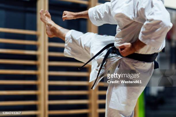 mature man kicking while practicing karate in class - karateka stock-fotos und bilder