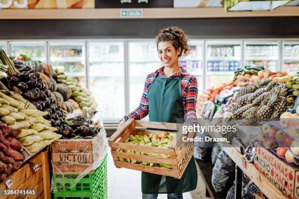 latin american employee - female greengrocer in supermarket during coronavirus pandemic - arranging stock pictures, royalty-free photos & images