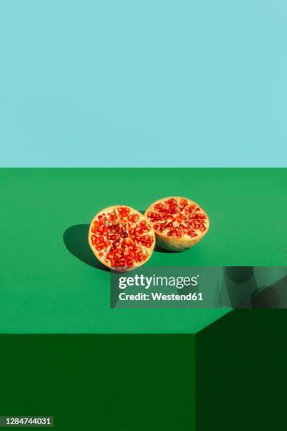 studio shot of halved pomegranate - food on coloured background stock pictures, royalty-free photos & images