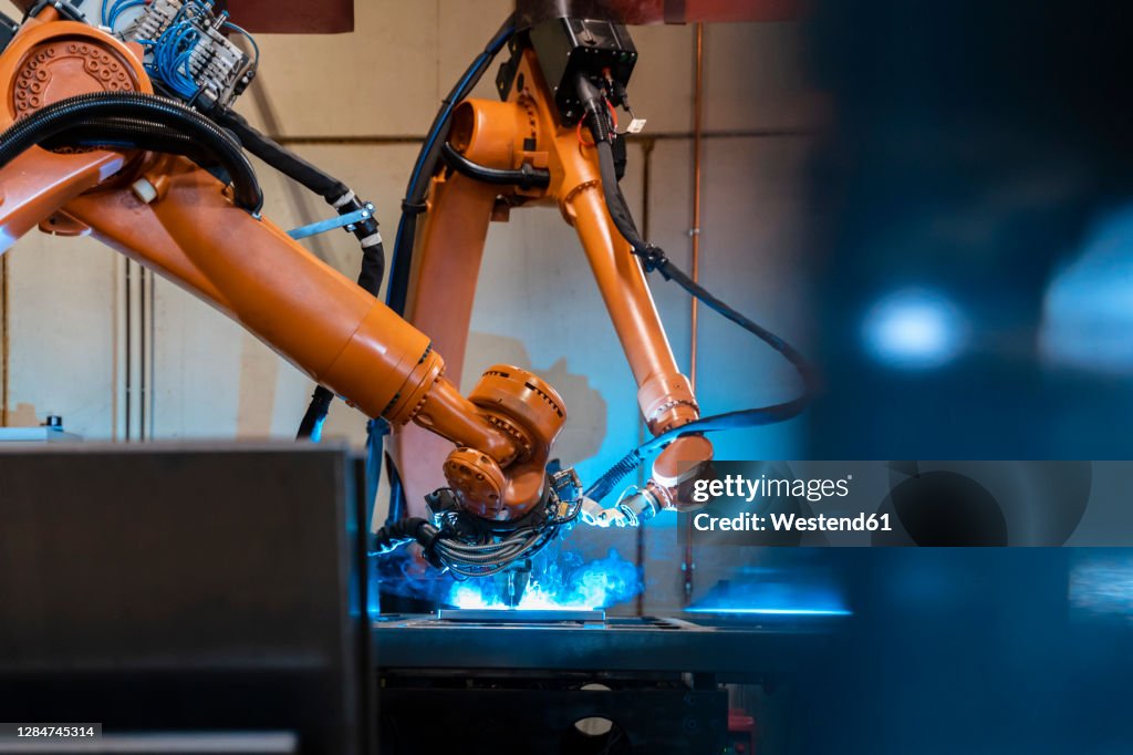Orange color robotic arms manufacturing in industrial factory