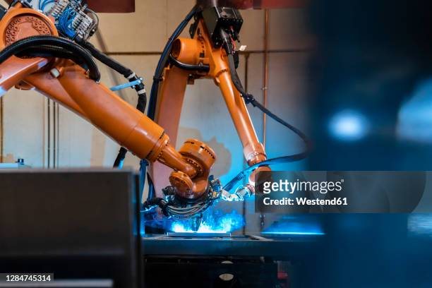 orange color robotic arms manufacturing in industrial factory - robot stock pictures, royalty-free photos & images