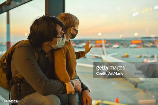 familie in schützenden gesichtsmasken am flughafen während der covid-19-pandemie - flughafen stock-fotos und bilder