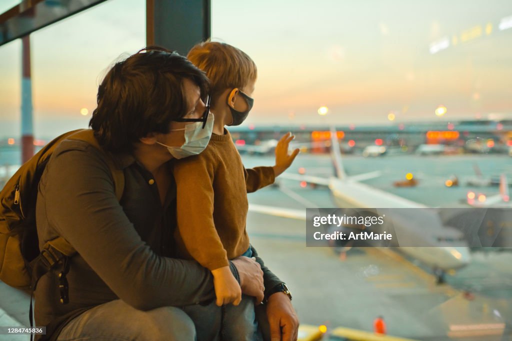 Familia con mascarillas protectoras en el aeropuerto durante la pandemia COVID-19
