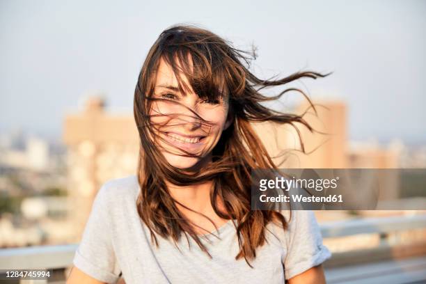 mature woman with hair blowing standing on building terrace - brown hair blowing stock pictures, royalty-free photos & images
