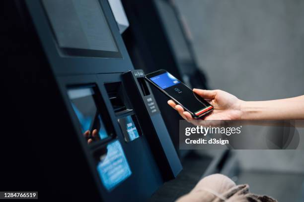 close up of a young asian woman using contactless payment via smartphone to pay for her shopping at self-checkout kiosk in a store - digital bank stock pictures, royalty-free photos & images