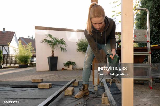 diy: weibliche teenager bohrt in eine planke für eine terrasse - steinterrasse stock-fotos und bilder