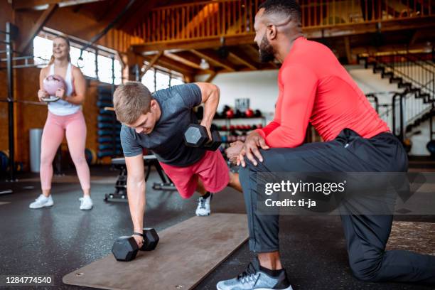 grupo de jóvenes haciendo ejercicio en el gimnasio - instructor-de-acondicionamiento-físico fotografías e imágenes de stock