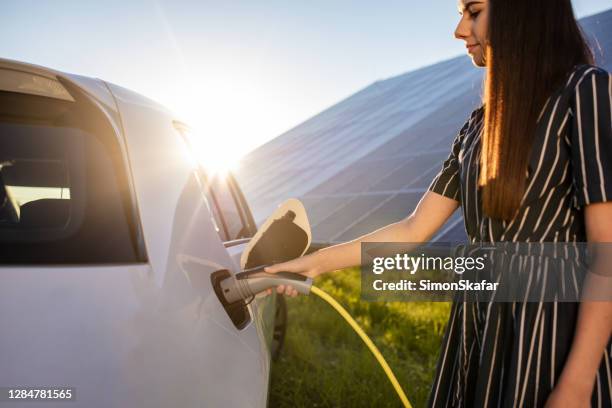 woman holding electric car charger - electric car charger imagens e fotografias de stock