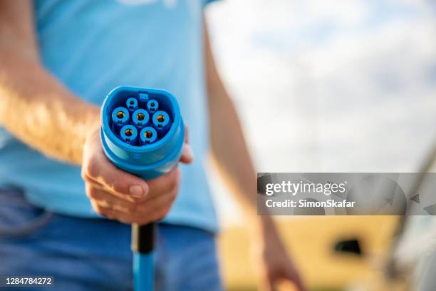 man holding electric charger - electric car charger imagens e fotografias de stock