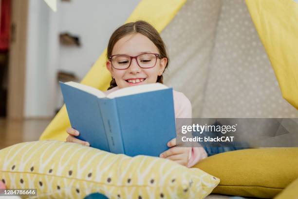 cute girl is reading a book at home on the floor - kids reading glasses stock pictures, royalty-free photos & images