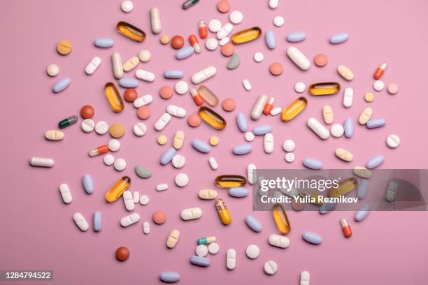 top view of spoon with various pills and tablets on the pink background - medicamento antiviral imagens e fotografias de stock