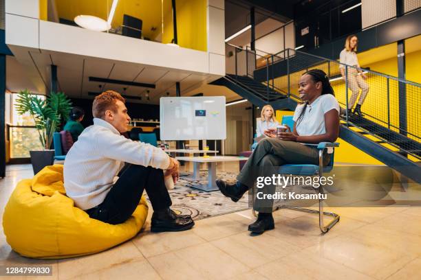 passionate creative director presenting her new ideas to a colleague while he carefully listening her - bean bags stock pictures, royalty-free photos & images