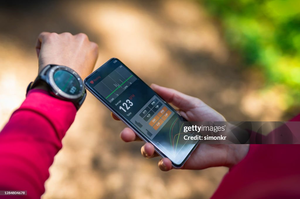 Woman synchronising smart watch and smartphone