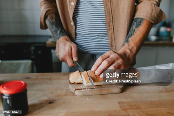 anonym ung man skära bröd i köket - en näring - göra en macka bildbanksfoton och bilder