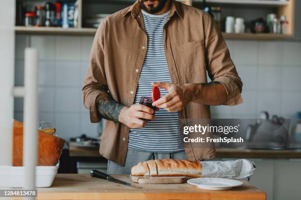 anonieme jonge man over om wat brood en jam te maken in zijn keuken - anonymous reporting stockfoto's en -beelden
