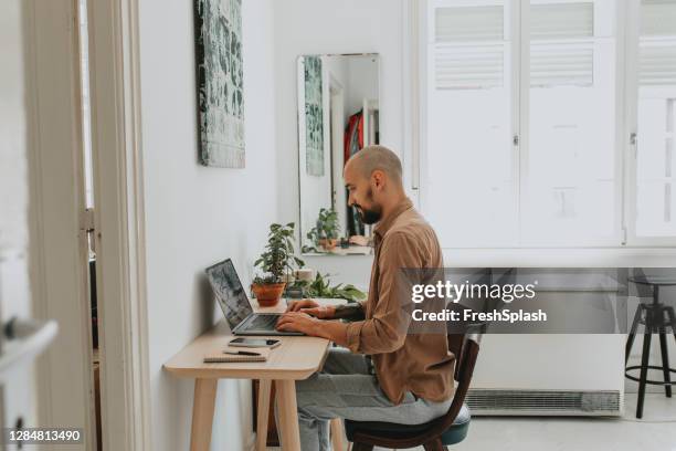 arbeiten von zu hause aus: junger geschäftsmann bereitet sich auf ein online-konferenztreffen vor, passt sich an das neue arbeitsumfeld an - die neue normalität stock-fotos und bilder