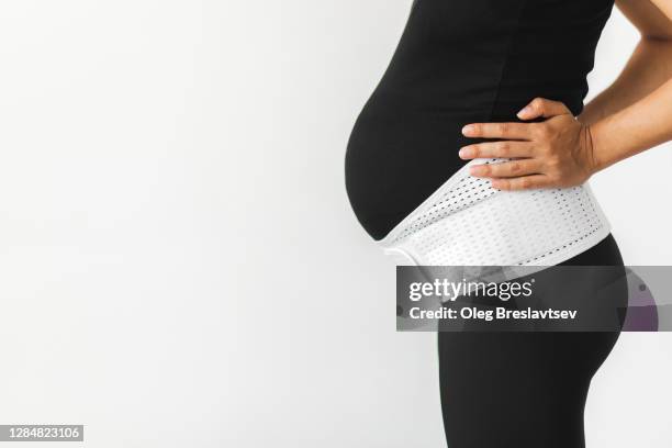 pregnant woman in support bandage medical corset close up. unrecognisable person. - orthopedic corset stock pictures, royalty-free photos & images