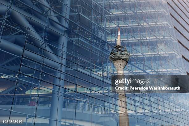 exterior and low angle with detail of reflecting rheinturm, rhine tower, on glass building's facade of stadttor tower against blue sky. - düsseldorf fotografías e imágenes de stock