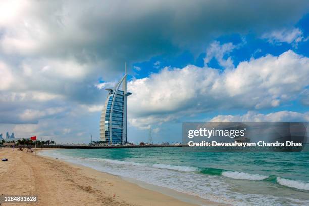 dubái, emiratos arabes unidos - umm suqueim beach bastante desierta temprano en la mañana. al fondo, el emblemático hotel burj al arab y a lo lejos algunos edificios en la isla de palm jumeirah. copiar espacio. - hotel jumeirah beach fotografías e imágenes de stock