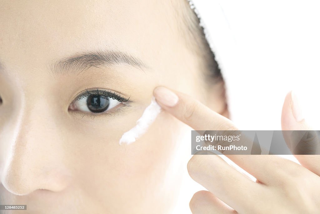 Young woman applying cream on face