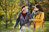 Senior woman with lovely girl wearing face mask at park