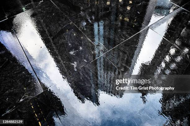 reflections in the wet sidewalk of modern office skyscrapers in the city of london - capitalismo foto e immagini stock