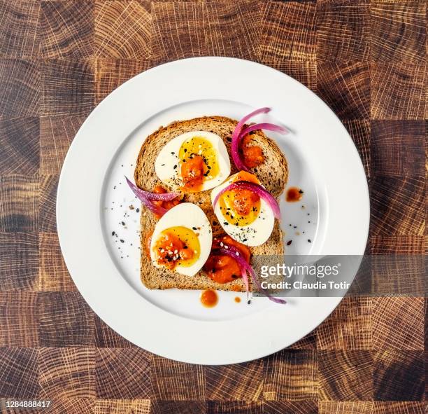 toast with boiled eggs on a plate on wooden background - hard boiled eggs stock-fotos und bilder