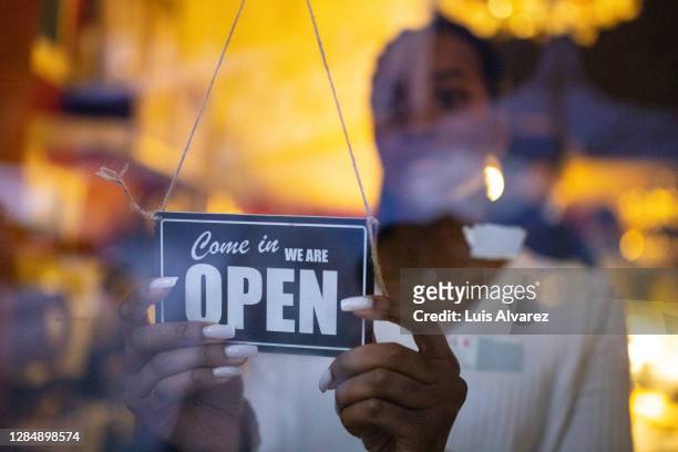 business owner hanging an open sign at a cafe - inaugurazione foto e immagini stock