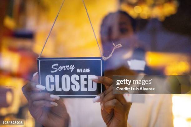 woman putting closed sign on door of coffee shop - chiuso foto e immagini stock