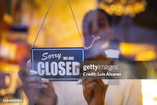 Woman putting closed sign on door of coffee shop Woman putting closed sign on door of coffee shop
