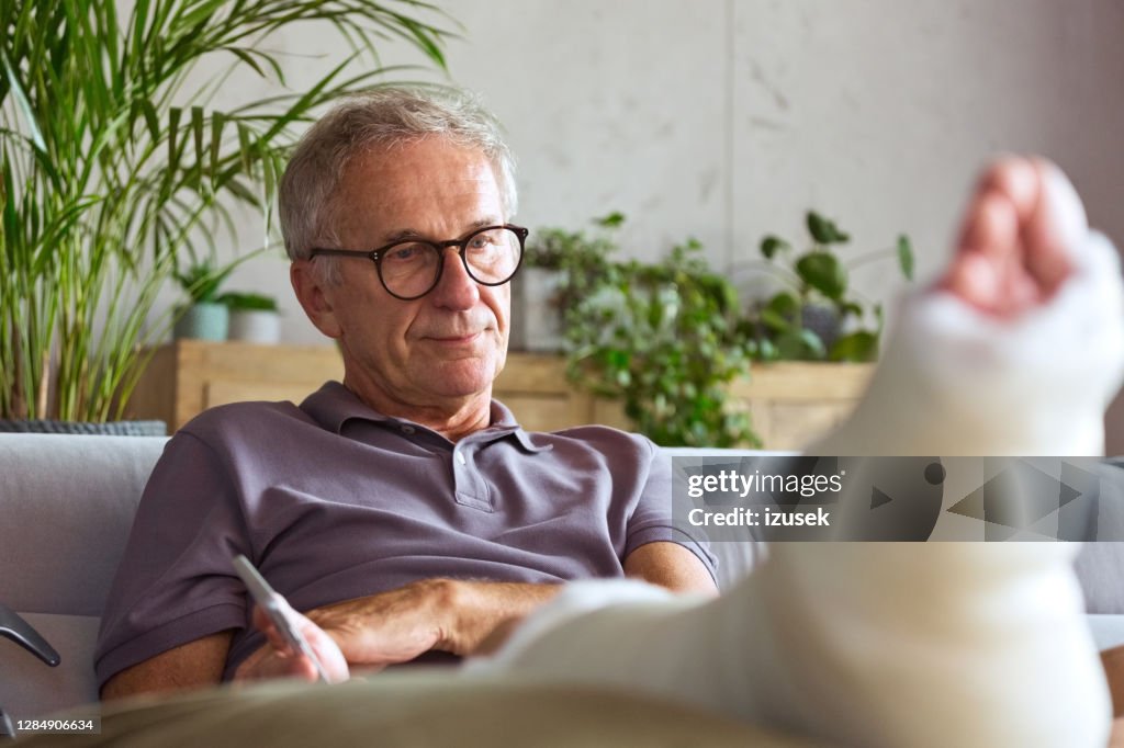 Besorgter Senior mit gebrochenem Bein zu Hause
