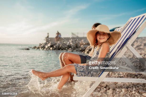 glimlachend meisje in zonhoed op ligstoel op strand - croatia coast stockfoto's en -beelden