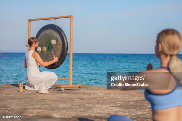 mujer haciendo yoga en la costa - gong fotografías e imágenes de stock