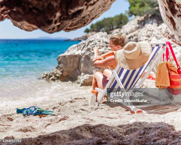 playa con algunos accesorios para tomar el sol - bolsa de cor creme fotografías e imágenes de stock