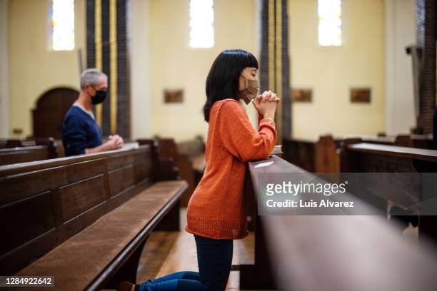 people in church praying with covid-19 restrictions - congregation stockfoto's en -beelden