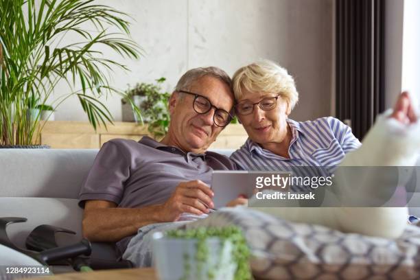 hombre mayor con la pierna rota en casa y su esposa - pierna fracturada fotografías e imágenes de stock