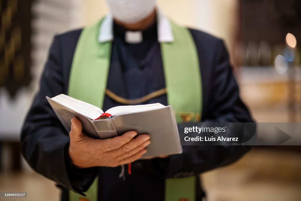 Priest reading bible during congregation in church